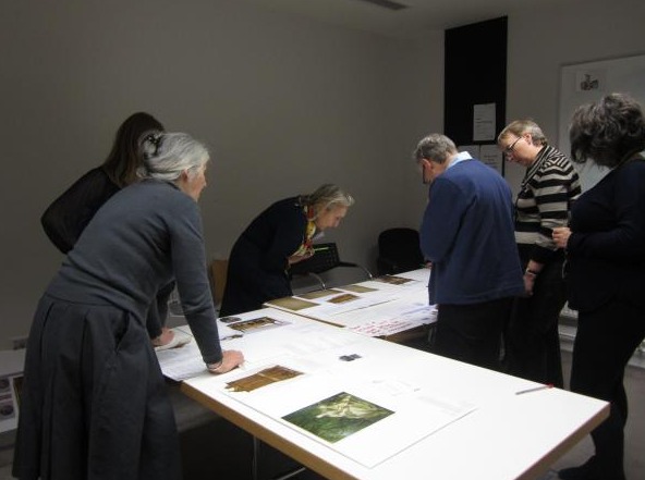 High school student writing exhibition labels and arranging prints on a table.